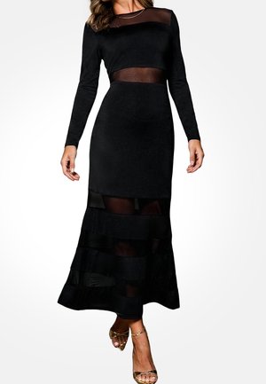 Czarna sukienka z długim rękawem z przezroczystymi panelami z siateczki i falbanami na dole. Wykonana z gładkiej tkaniny, o dopasowanym kroju.