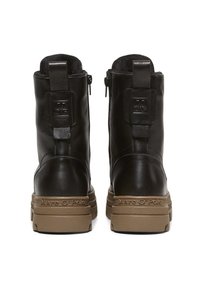 Paire de bottines en cuir noir avec semelles en caoutchouc beiges, estampillées "Marc O'Polo" sur le talon, vues de dos.