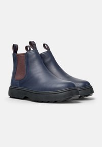 Cizme de glezna din piele bleumarin, cu panouri elastice laterale, bucle pentru tragere și tălpi din cauciuc negru rezistent, prezentând un model de bandă de rulare în zigzag.
