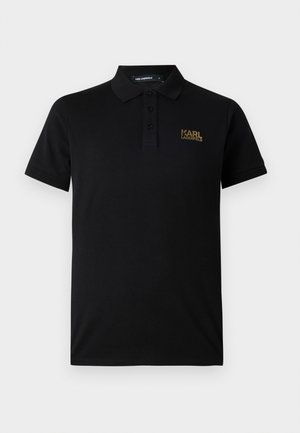 Schwarzes Polohemd aus Baumwolle mit kurzen Ärmeln, ausgestattet mit einer Knopfleiste mit drei Knöpfen und einem goldenen Logo auf der linken Brust. Smoother Stoff.