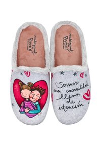 Un par de zapatillas de casa grises y peludas con una pareja de caricatura abrazándose dentro de un corazón rojo en una, y texto en español en la otra con pequeños corazones rojos.