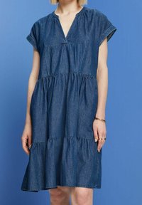 Denim dress with a V-neckline, short sleeves, and tiered ruffle hem. Dark blue fabric with a subtle texture. Mid-length design.