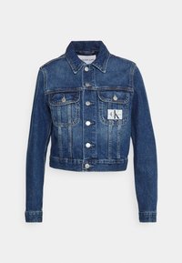 Jeansjacka i mörkblått, kortare design med knappstängning, två bröstfickor och en logotyp på vänster sida.