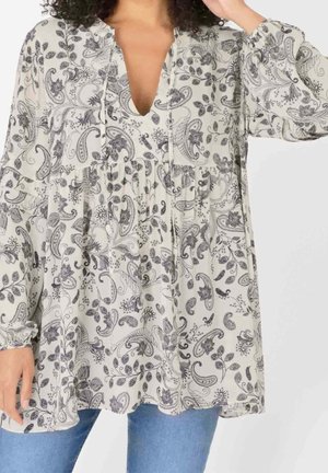 Blusa leggera in crema con motivo paisley nero, scollatura a V e vita arricciata. Presenta maniche lunghe e vestibilità ampia.