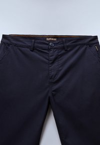 Pantalones azul marino hechos de material ligero, con cierre de botón, bolsillos delanteros y costuras en contraste en la cintura.