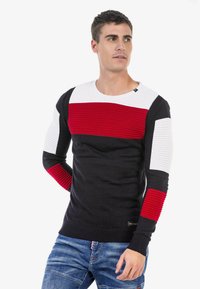 Herren Strickpullover mit rundem Ausschnitt, geripptem Muster und kräftigen Farbblocks in Schwarz, Rot und Weiß. Abgerundet mit strukturierten Ärmeln.