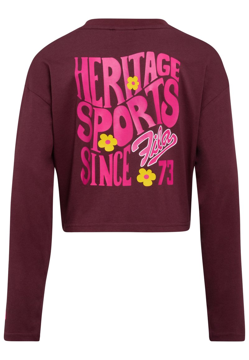 Camicetta corta a maniche lunghe color marrone con testo rosa e giallo "HERITAGE SPORTS DAL 73" e logo "Fila", decorata con fiori gialli.