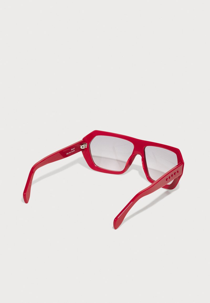 Rote Sonnenbrille mit einem klobigen, geometrischen Rahmen, ausgestattet mit getönten Gläsern und dicken, geraden Bügeln. Auffällige Akzentdetails an den Bügeln.
