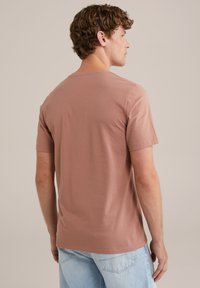 Rövid ujjú, kerek nyakú póló púder rózsaszín színben. Puha pamutból készült, sima tapintással és egyszerű, klasszikus dizájnnal.