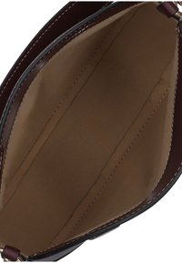 Gestructureerde handtasinterieur met een gladde bruine voering, voorzien van twee zijvakken en contrasterende donkere leren rand langs de rand.