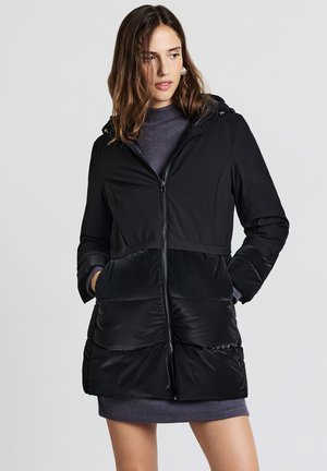 Giacca a piumino nera con zip frontale, cappuccio e pannelli testurizzati a contrasto. Presenta tasche inclinate e una finitura del tessuto leggermente lucida.