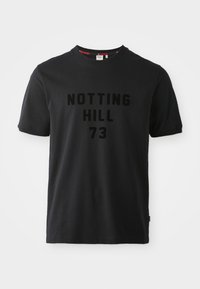 Svart t-skjorte med kort erme laget av bomull, med rund hals og hevet, tonet trykk som sier "NOTTING HILL 73" på forsiden.