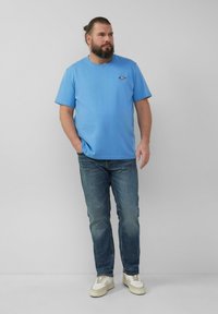 Lichtblauw katoenen T-shirt met korte mouwen en een klein logo, gecombineerd met donkerblauwe jeans en witte sneakers. Eenvoudig, ontspannen pasvorm ontwerp.