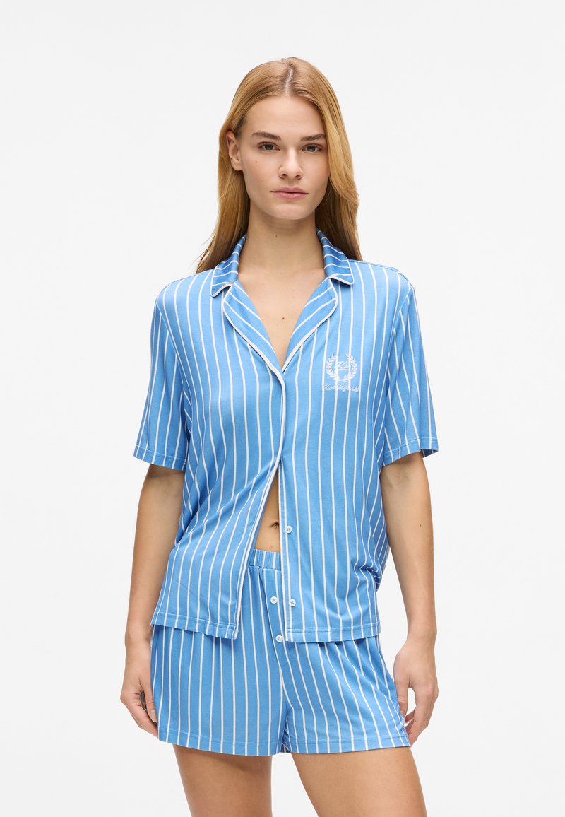 Ensemble de pyjama à manches courtes rayé bleu en tissu doux, comprenant une chemise à boutons et un short assorti avec un détail brodé simple.