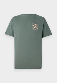 Green cotton t-shirt with short sleeves, round neckline, and a peach-colored graphic of a figure with a surfboard on the chest.