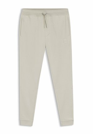 Pantalon de survêtement beige clair, fuselé, avec taille à cordon, poches latérales et petit logo carré sur l'avant de la cuisse droite.