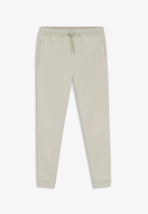 Pantalon de survêtement beige clair, fuselé, avec taille à cordon, poches latérales et petit logo carré sur l'avant de la cuisse droite.