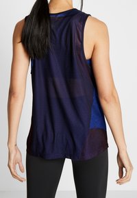 Top atletico senza maniche in tessuto a rete blu scuro con un pannello di colore blu più chiaro a contrasto e orlo arrotondato. Presenta una vestibilità comoda e una texture traspirante.