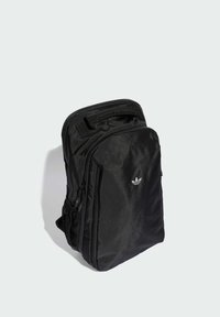 Svart ryggsäck i texturerat tyg med ett fack med dragkedja, en nätficka på sidan och en liten vit logga på framsidan.