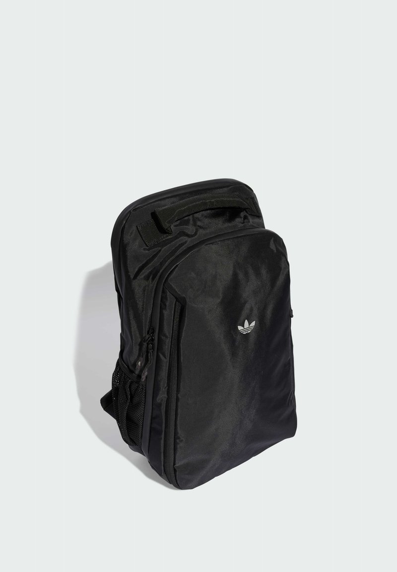 Svart ryggsäck i texturerat tyg med ett fack med dragkedja, en nätficka på sidan och en liten vit logga på framsidan.