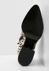 Stivale alla caviglia con stampa leopardata, punta appuntita, tacco nero lucido, zip laterale e superfice in tessuto texture.