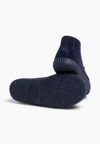 Botas de tobillo de ante azul marino con suelas de goma texturizada, que presentan un diseño simple y costuras reforzadas a lo largo de las costuras para mayor durabilidad.