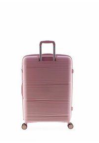 Hardshell suitcase in light pink with horizontal grooves, a retractable metal handle, and four smooth-rolling wheels.