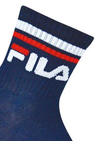 Calcetines azul marino con puño a rayas blancas y rojas. Presentan un logo blanco tejido en la tela. Textura suave, longitud a media pantorrilla.