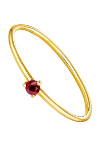 Pulsera bangle en tono dorado que presenta una gema roja redonda, montada en un soporte de cuatro garras, con una superficie suave y pulida.