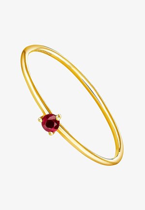 Pulsera bangle en tono dorado que presenta una gema roja redonda, montada en un soporte de cuatro garras, con una superficie suave y pulida.