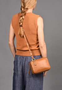 Bolso bandolera de cuero marrón con forma rectangular, cierre en la parte superior y correa ajustable. Presenta detalles en hardware dorado y un acabado texturizado.