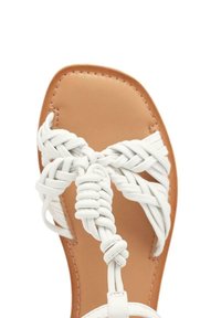 Sandali bianchi intrecciati con un design a tessuto e una soletta liscia color beige. Suola piatta con cinghie incrociate davanti e una cinghia alla caviglia sicura.