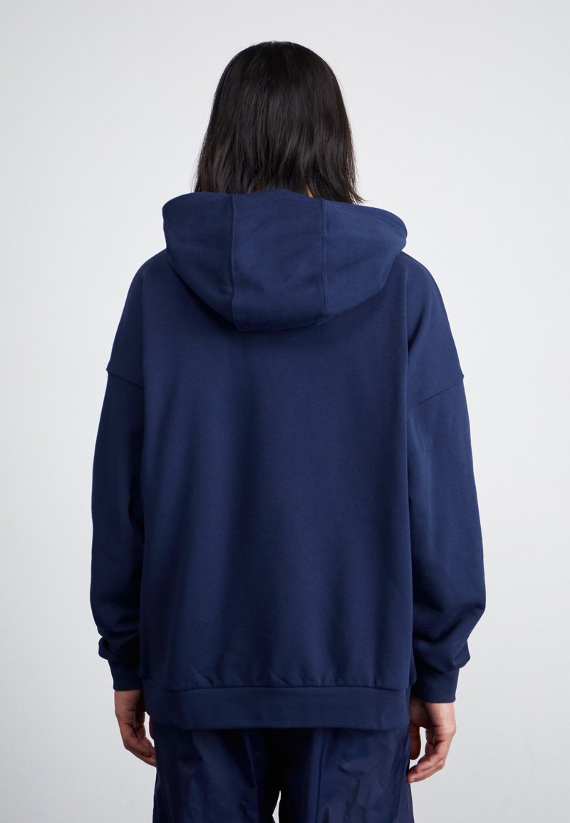 Granatowa, oversize bluza z dużym kapturem, prążkowanymi mankietami i dołem. Wykonana z miękkiego materiału, charakteryzująca się przestronnym, luźnym krojem.