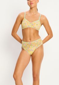 Bralette en dentelle florale colorée avec des bretelles bleu clair et un bas taille haute assorti, présentant un tissu texturé et un bord contrastant.