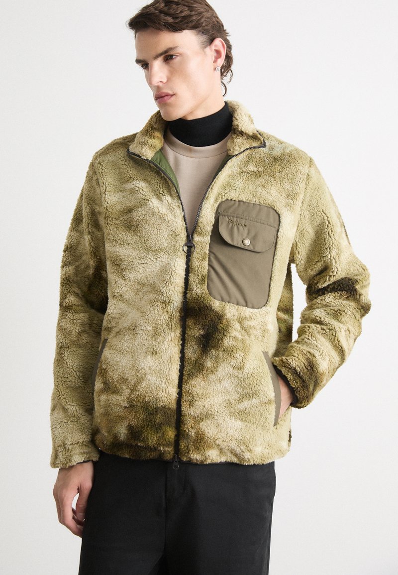 Fleece jack in olijfgroen met een getextureerde, pluche buitenkant. Beschikt over een rits aan de voorkant, zijzakken en een contrasterende utility-stijl borstzak.
