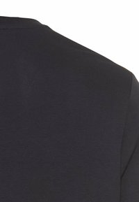 Zwarte katoenen t-shirt met een gladde textuur, voorzien van een klassieke ronde hals en korte mouwen, waarbij alleen een deel van het schoudergebied zichtbaar is.