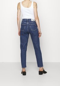 Högmidjade mörkblå denimjeans med raka ben, fem fickor och en märkesskärp med en jämn yta.