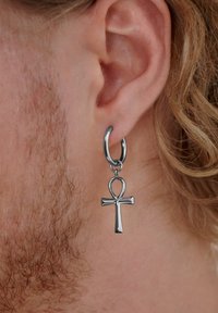 Sølv hoop ørering med en ankh-symbol vedhæng. øreringen har en poleret overflade, og vedhænget viser et glat, symmetrisk design.