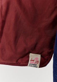 Červená a modrá látka s hladkým povrchem; obsahuje štítek s nápisem "lovexoxo a další barvy" vytištěným v růžové a černé.