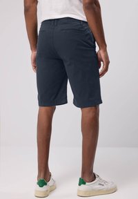 Mörkblå shorts i ett lättviktsmaterial, med en klassisk design som har bakfickor och en skräddarsydd passform, som slutar ovanför knäet.