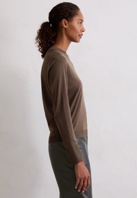 Bruine langemouwen top met een ronde halslijn, gemaakt van zacht materiaal. Heeft een slim fit, een gladde textuur en wordt gecombineerd met grijze broek.