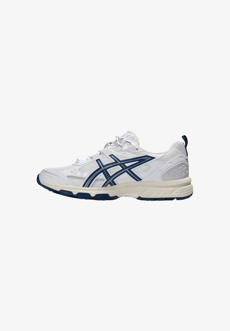 Chaussure de sport blanche avec des bandes bleu marine et une semelle beige, conçue pour la course ou pour un usage décontracté, montrée de côté sur un fond blanc.