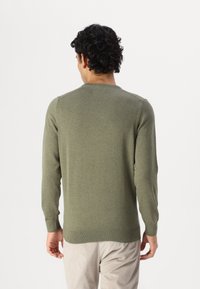 Olajzöld, hosszú ujjú kötött pulóver, kerek nyakkivágással és bordázott mandzsettával. Simább textúra, minimalista dizájn, látható minták vagy díszítések nélkül.