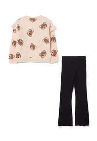 Lichtroze sweatshirt met bruine berenprint en ruffle mouwen, gecombineerd met zwarte aansluitende broek met uitlopende pijpen.