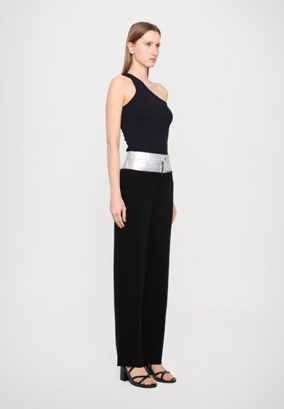 Zwarte mouwloze top, zilver metallic riem, hoge zwarte broek en zwarte haksandalen. Minimalistisch ontwerp met contrasterende elementen.