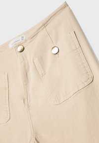 Beige bukser med en blød tekstur, der har to forlommer med metalknapper og et lige ben design. Størrelsesmærke synligt.