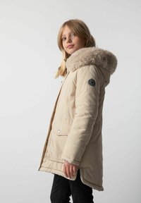 Beżowa ocieplana kurtka z kapturem z sztucznym futrem, z przednimi kieszeniami i naszywką z logo na rękawie. Gładka faktura z lekko błyszczącym wykończeniem.