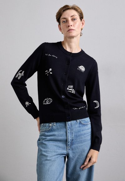 Cardigan blu navy con motivi ricamati, tra cui una macchina fotografica e una luna. Presenta un collo rotondo, maniche lunghe e chiusura con bottoni. Testo sulla manica.