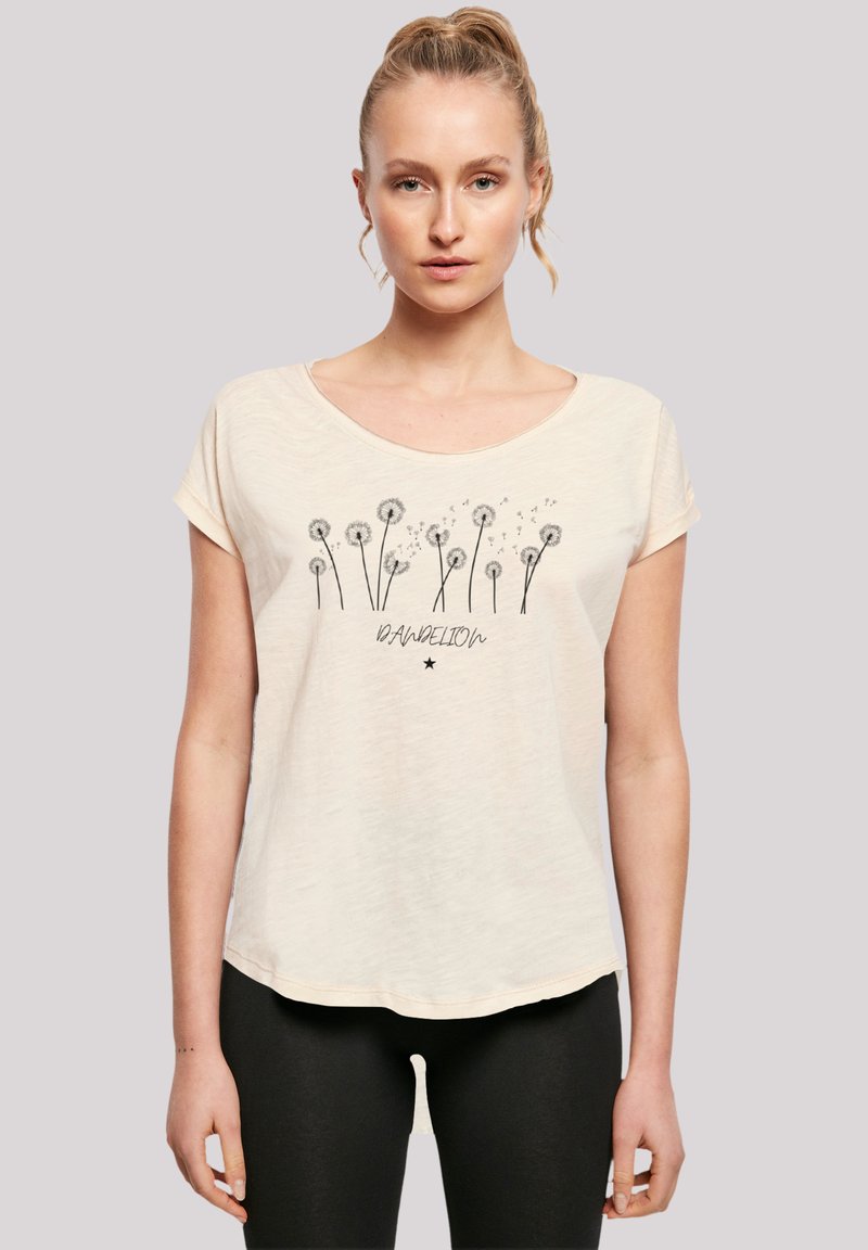 Lichtbeige t-shirt met korte mouwen en een wijde halslijn. Heeft een zwarte paardenbloemafbeelding en de tekst "DAWDELION" gedrukt op de voorkant.