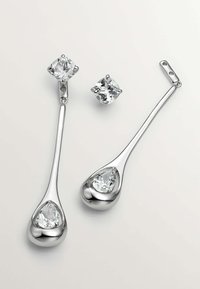 Conjunto de pendientes en tono plateado que presenta un par de pendientes colgantes con piedras preciosas transparentes en forma de pera y redondas, acabado pulido y diseño elegante.